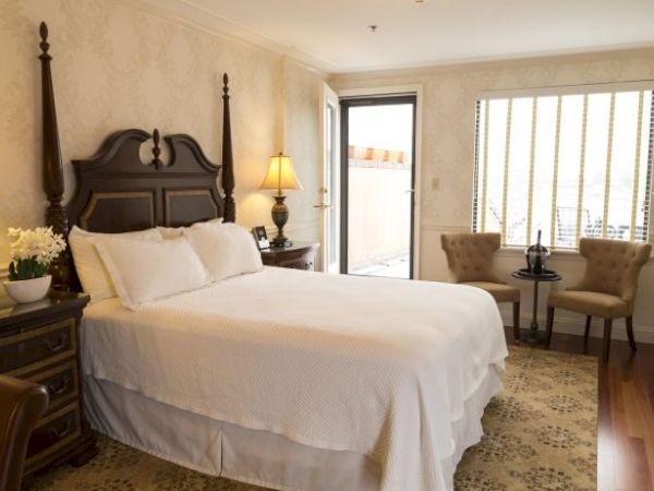 A cozy bedroom with a double bed, lamps on bedside tables, chairs by the window, a dresser, and soft lighting.