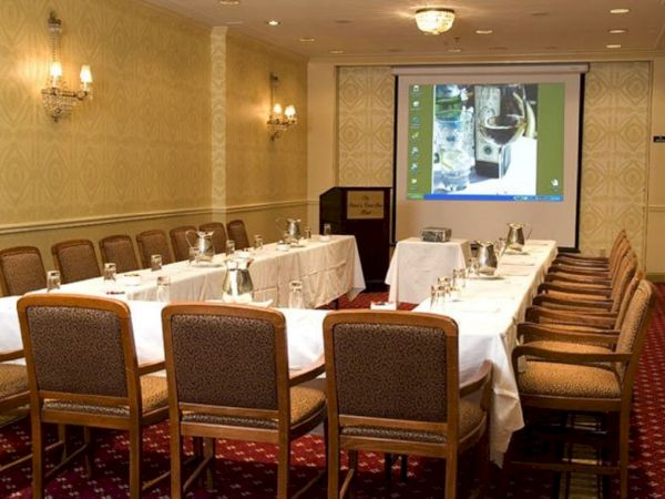 A conference room with arranged chairs, tables, and a screen displaying a presentation, ready for a meeting or event.