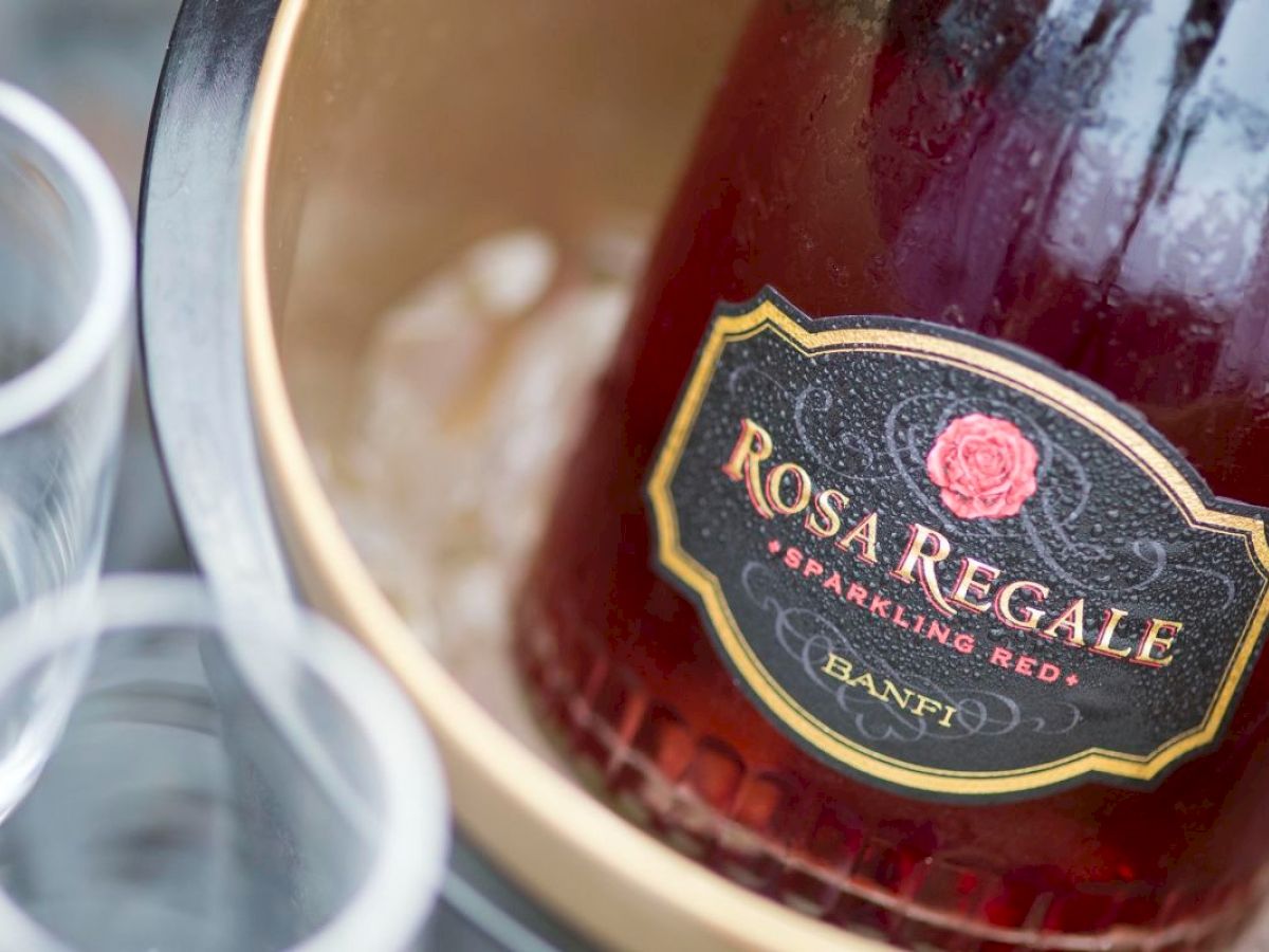 A bottle of Rosa Regale sparkling red wine in an ice bucket, with two empty glasses beside it.