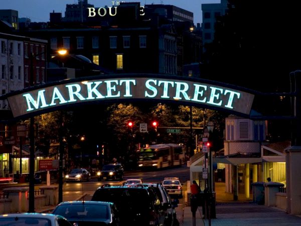 The image shows a street scene at night with a sign reading "Market Street" lit up, and cars and shops visible below.