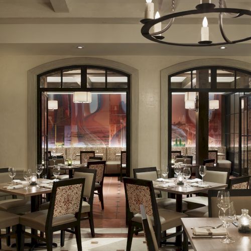 The image shows a sophisticated restaurant interior with elegant tables, chairs, and a chandelier, creating a cozy ambience.