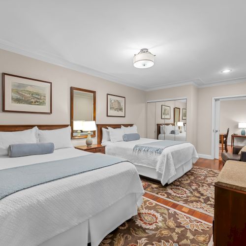 Bed and nightstands in a bright hotel room with a desk, chair, and chandelier&mdash;cozy yet airy.