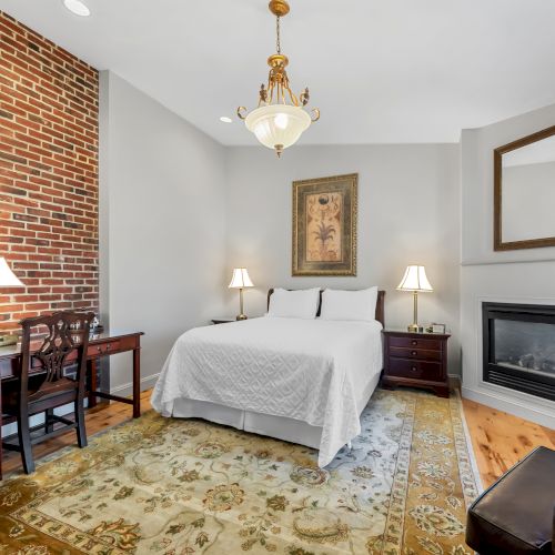 A cozy bedroom with a white tufted bed, warm wood flooring, a wooden dresser, a slanted ceiling with skylight, and soft, inviting decor.