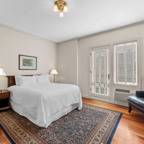 A cozy bedroom with a wooden floor, white bed, bedside tables, gray walls, and a skylight window giving a warm daylight vibe.